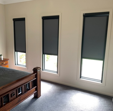 grey blinds partially covering three windows in a bedroom