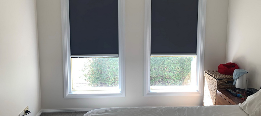 two black blinds partially covering windows in a bedroom