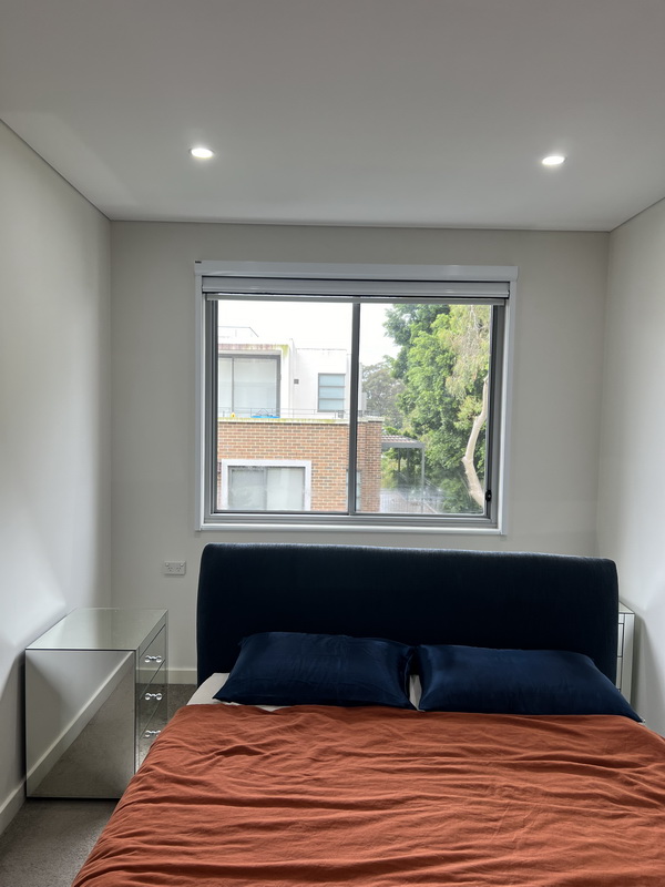 bright bedroom with a window with roller blinds all the way up