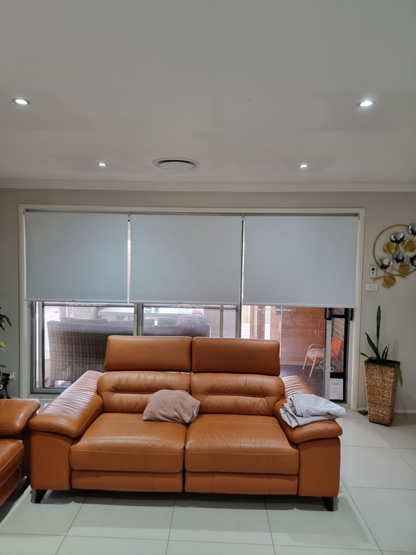 living room with patio door and windows half covered with indiana roller blinds