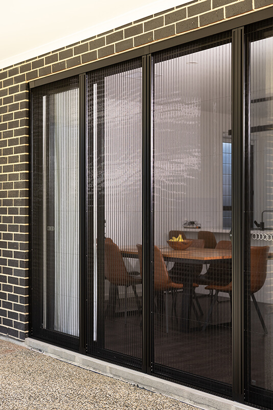 Person closing a vertical slatted window screen.