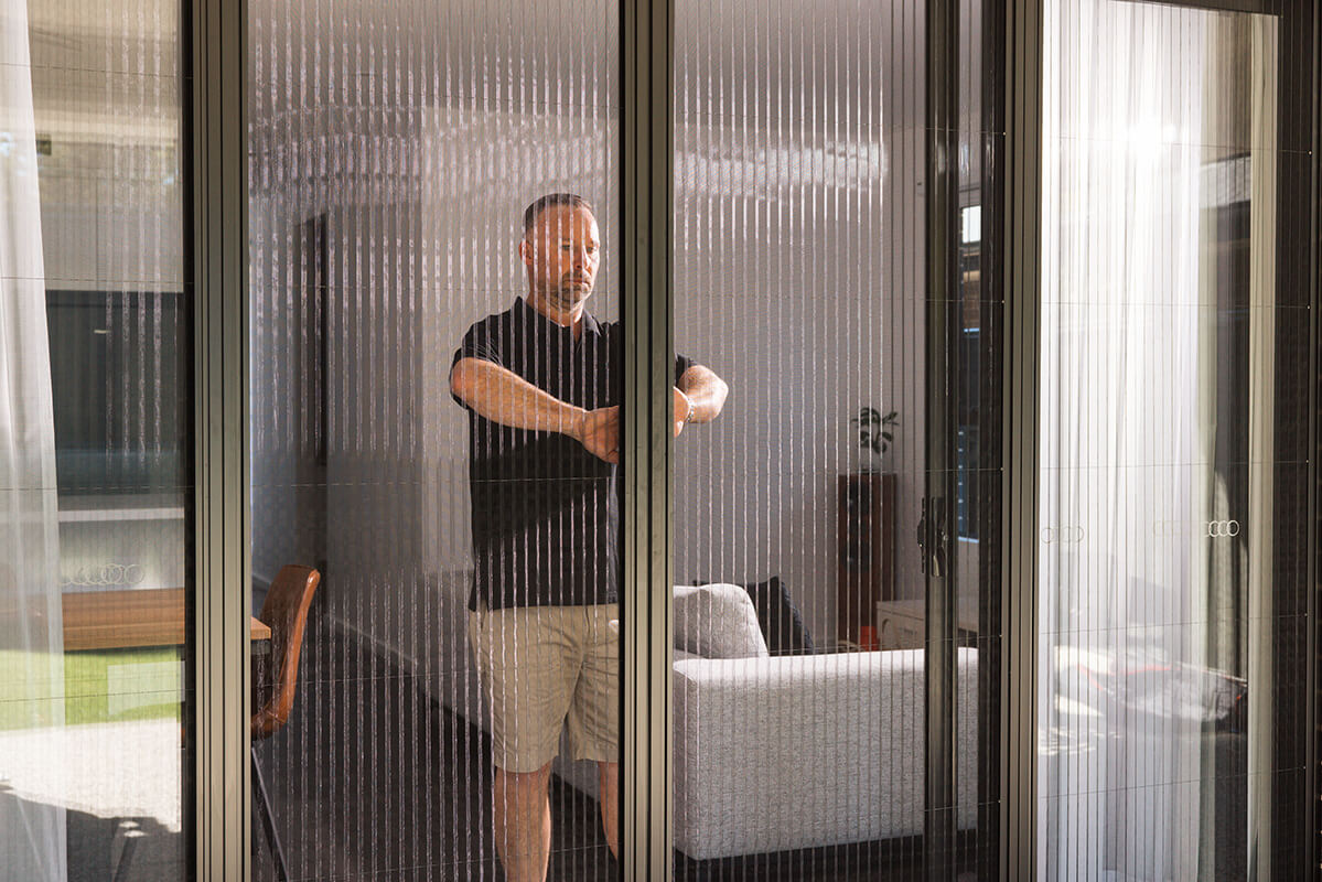 Person closing a vertical slatted window screen.